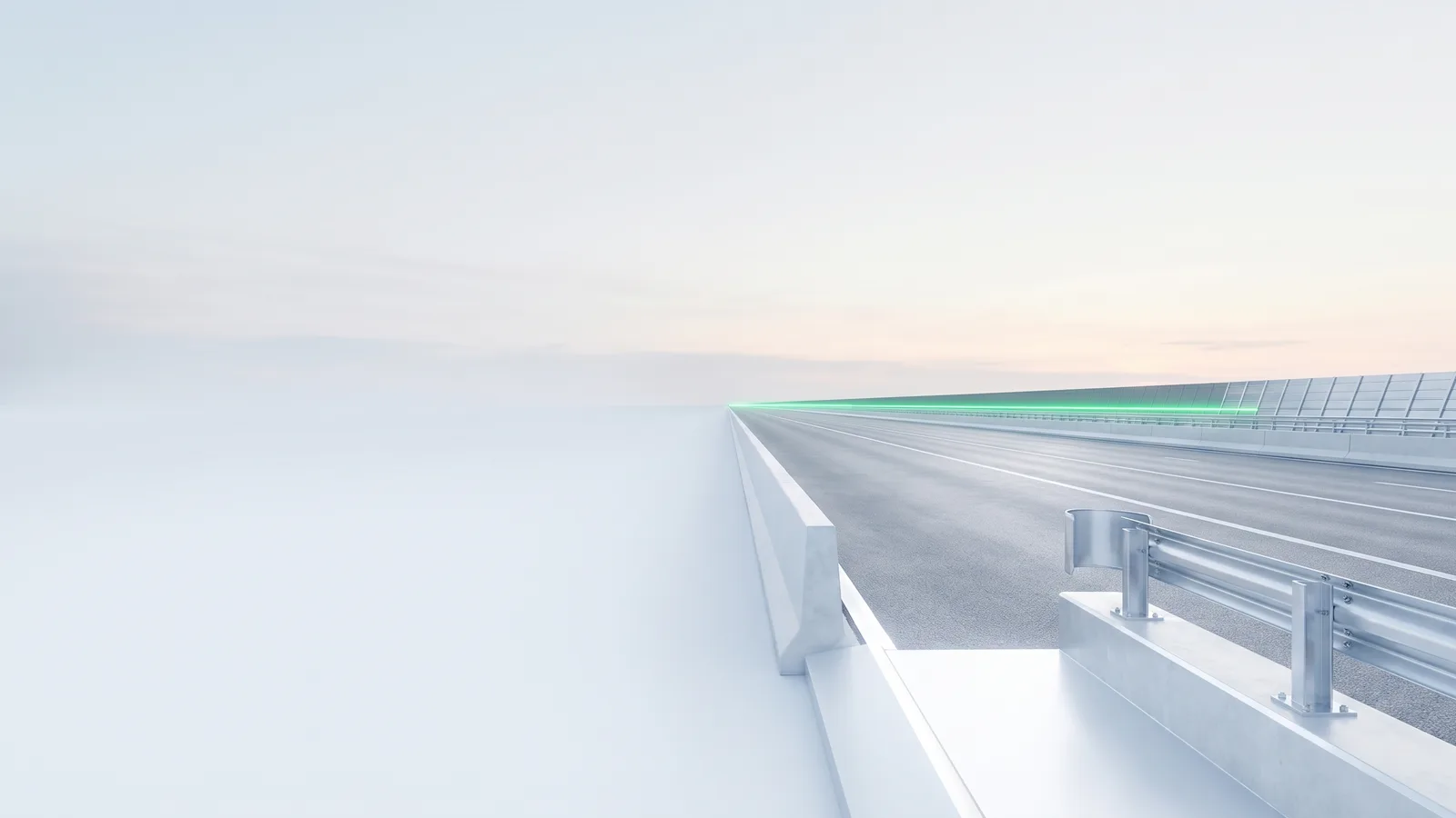 A pale road running into haze beside a white crash barrier, a green line along the far edge.