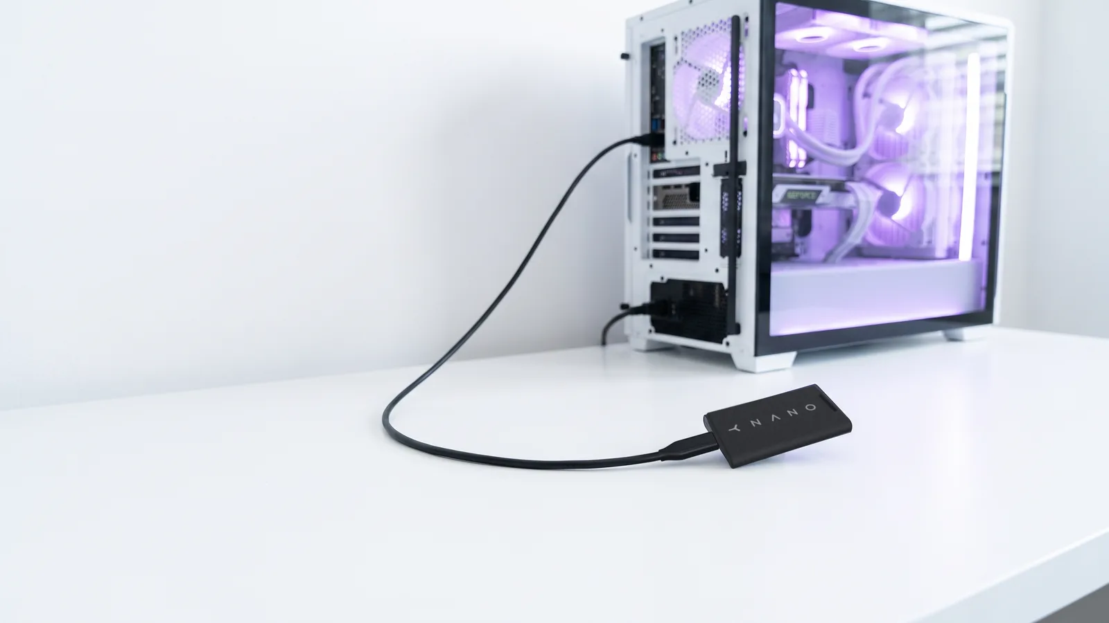 A YOM NANO on a white desk, plugged into a white gaming PC with a black USB-C cable.